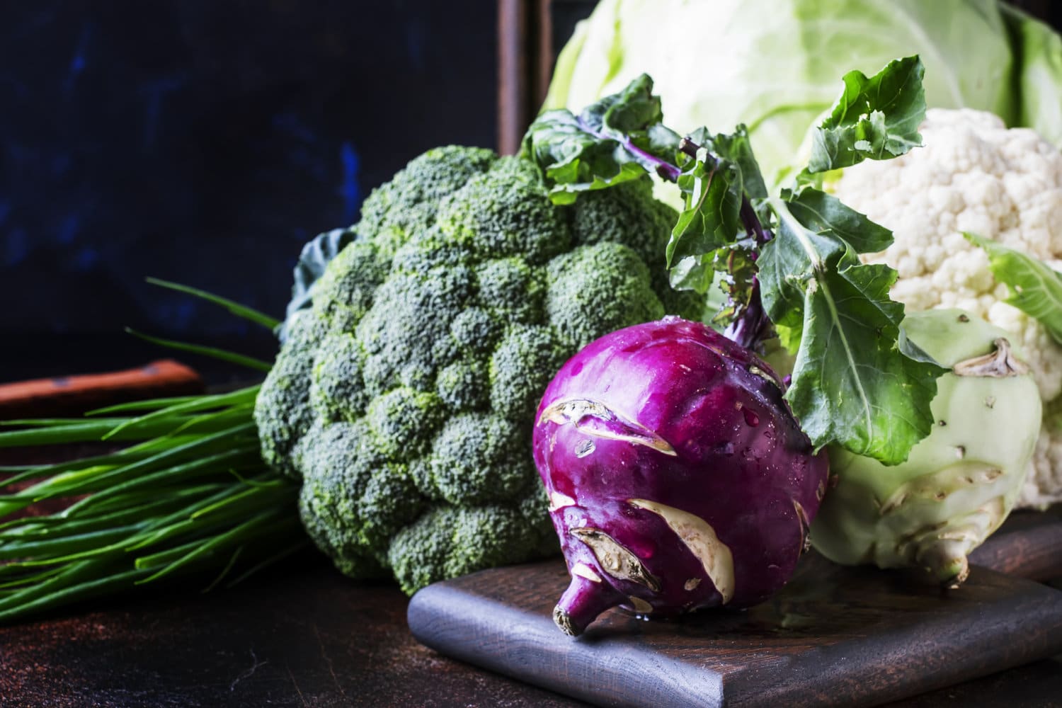 White cabbage, cauliflower, broccoli, kohlrabi on dark table, autumn harvest, selective focus